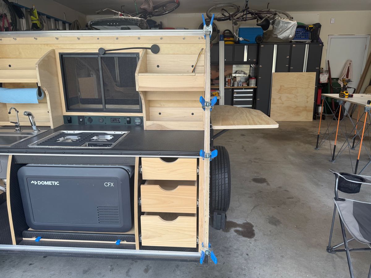 A teardrop galley slide rolled forward so the chest fridge lid opens fully clear of the countertop