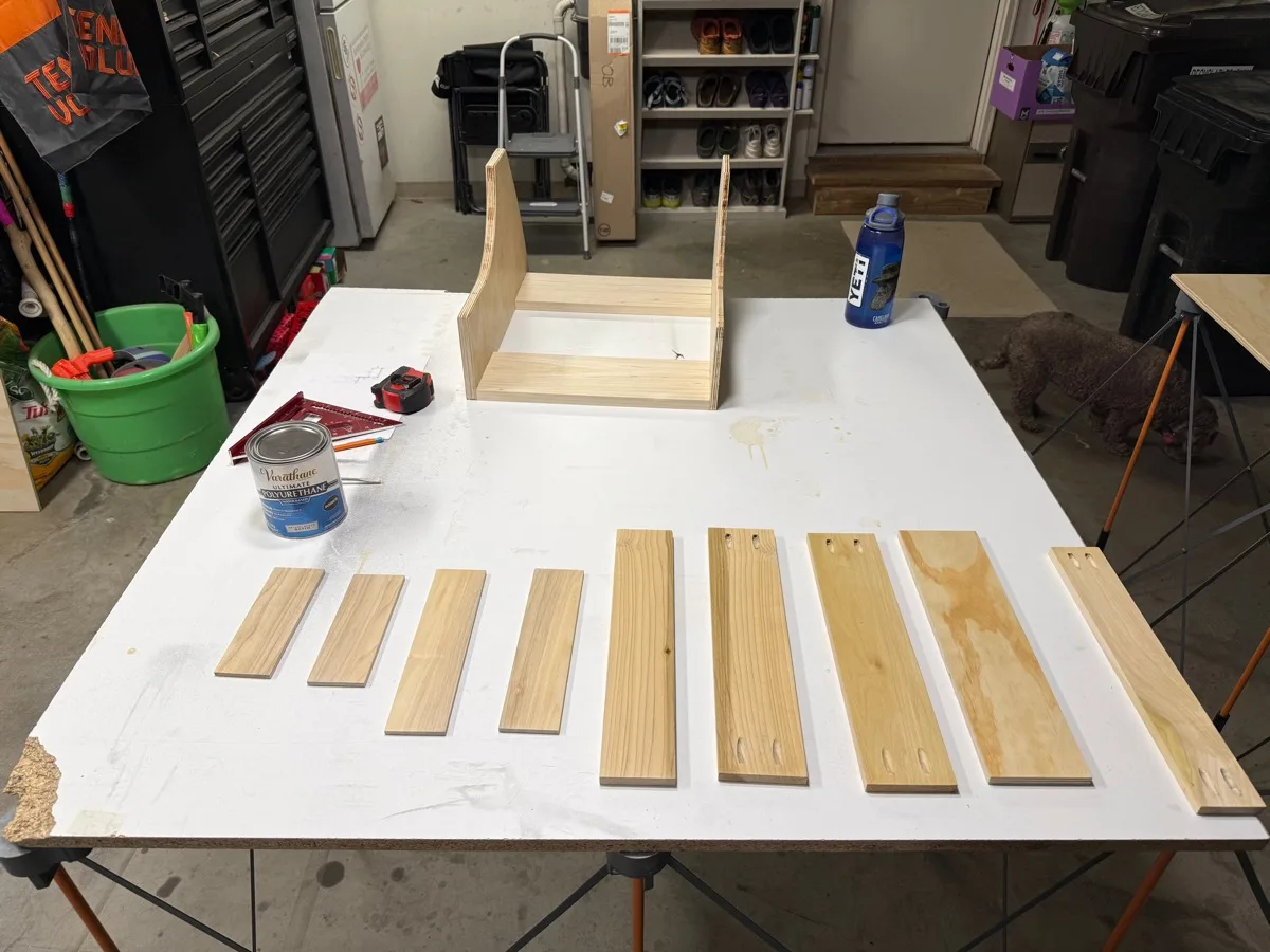 Galley shelf parts cut from a mix of Baltic birch and poplar, laid out on a workbench next to a can of finish