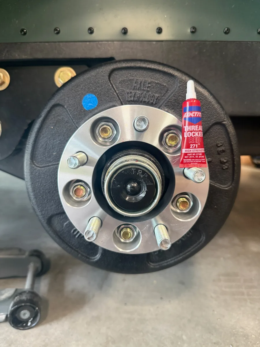 Hub-centric wheel spacer bolted onto the trailer hub with a tube of red threadlocker beside it