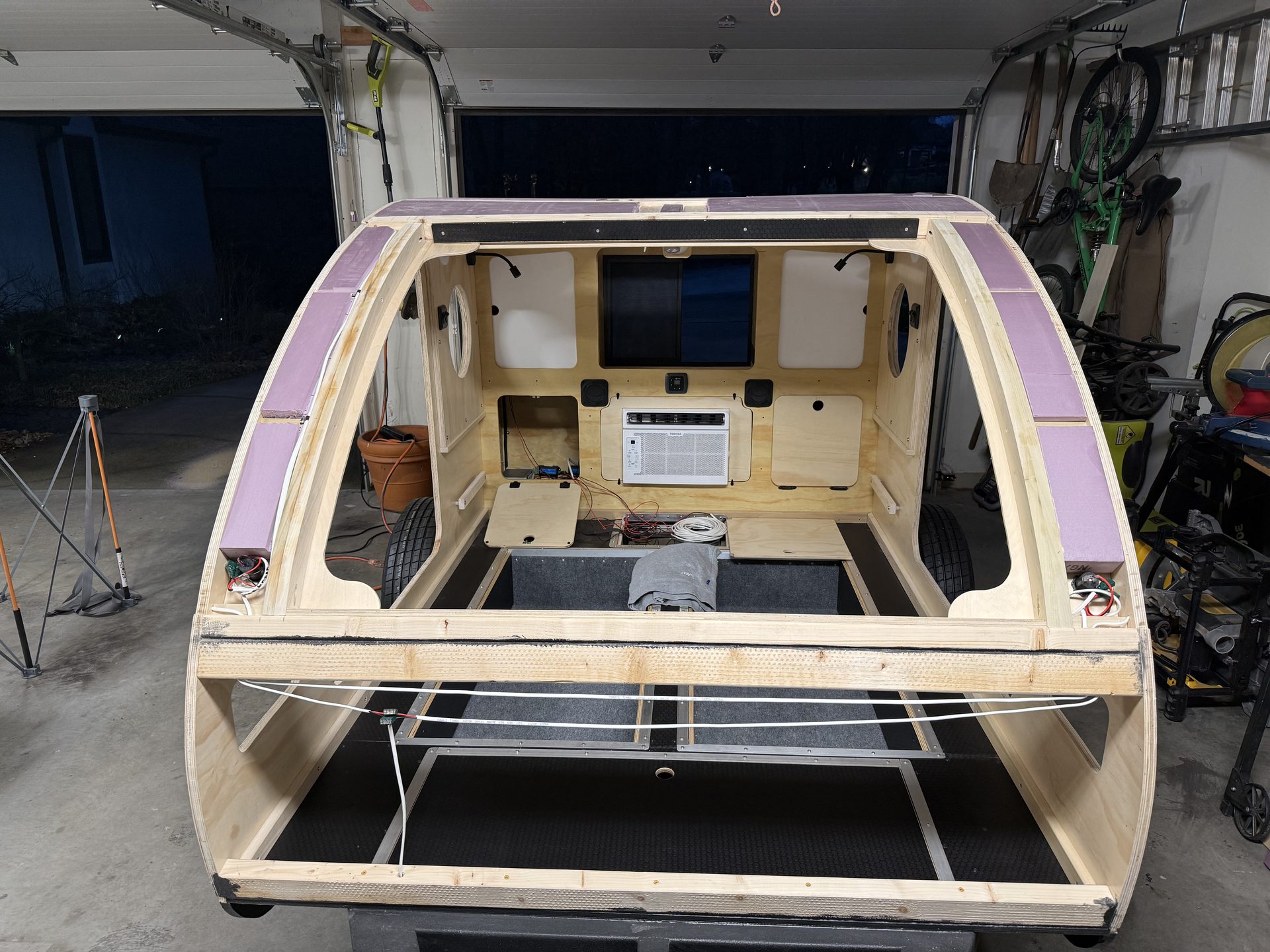 Rigid foam board fitted between the curved roof spars of a teardrop camper before the roof skin is installed